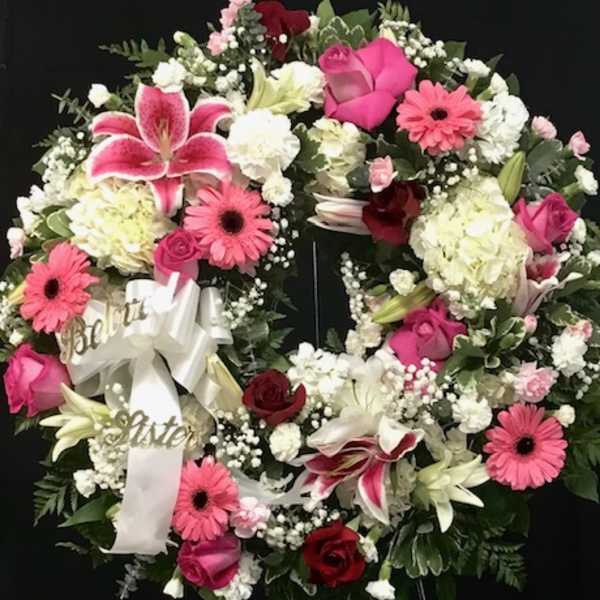 Heart-shaped floral wreath with pink and white flowers on a black stand