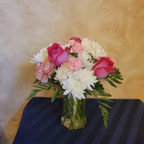 Pink roses and white chrysanthemums arranged in a glass vase