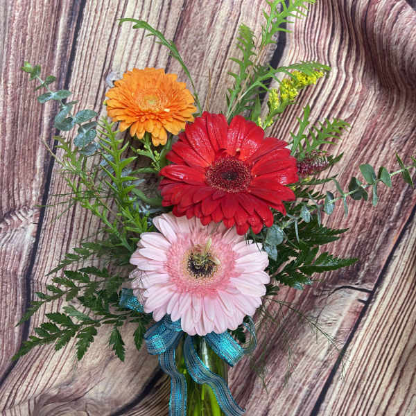 Gerbera daisy bouquet in a glass vase with a blue ribbon