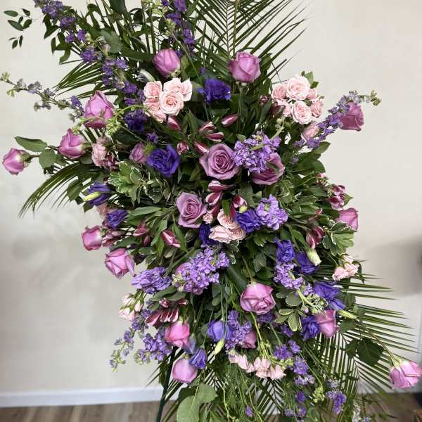 Tall floral spray with pink and purple roses and mixed blooms on a stand