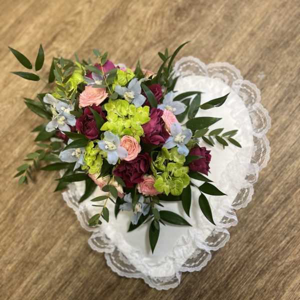 Bouquet of pink, burgundy, and lime flowers on white lace fabric