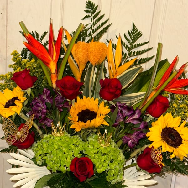 Mixed bouquet with red roses, sunflowers, and tropical blooms in a vase