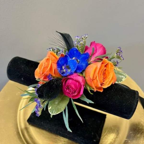 Small bouquet of orange, pink, and blue flowers on a black stand