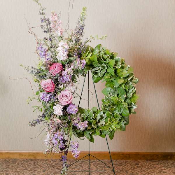 Floral wreath on a stand with pink and purple flowers and green foliage