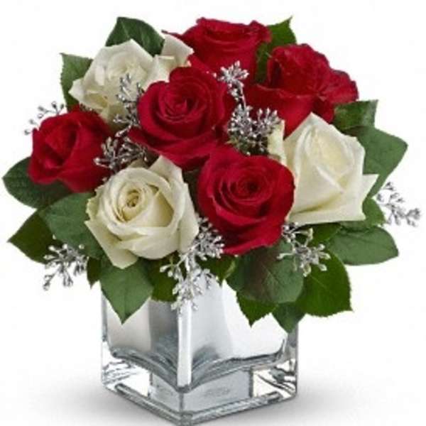Red and white roses in a clear square vase