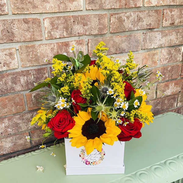 Bouquet of red roses and yellow sunflowers in a white box