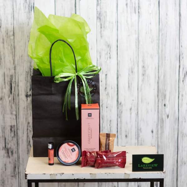 Gift bag with tissue paper, candles, and candy on a small table