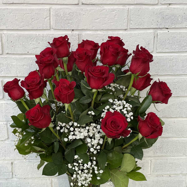 Red roses arranged in a clear glass vase with white baby's breath
