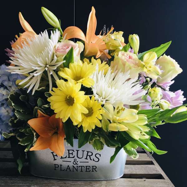 Mixed bouquet in a metal container with lilies, daisies, roses, and hydrangea