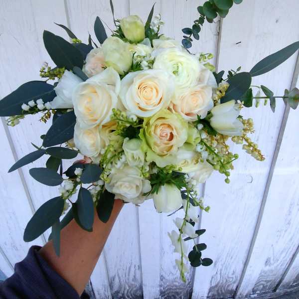 Handheld bouquet of white roses and pale blooms with dark foliage