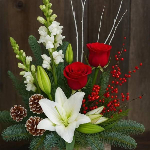 Holiday arrangement with red roses, white lilies, and pinecones in a wooden box