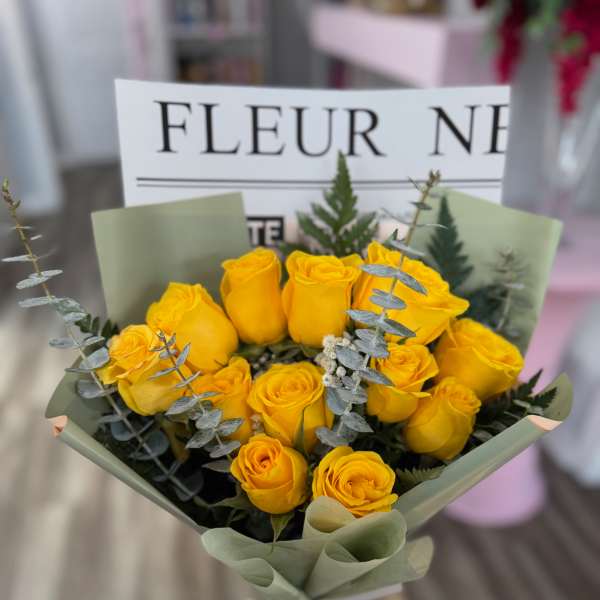 Bouquet of yellow roses wrapped in pale green paper