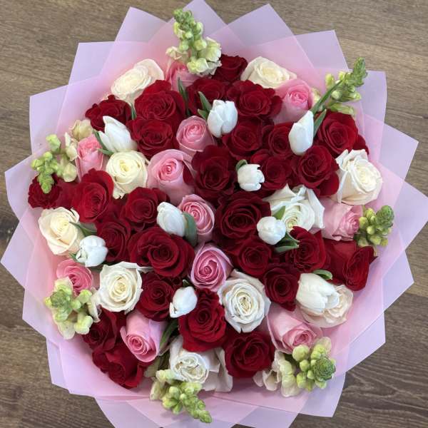 Bouquet of red, pink, and white roses wrapped in pink paper