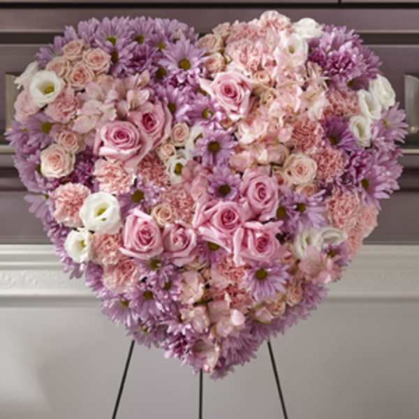 Heart-shaped arrangement of pink and lavender flowers on an easel