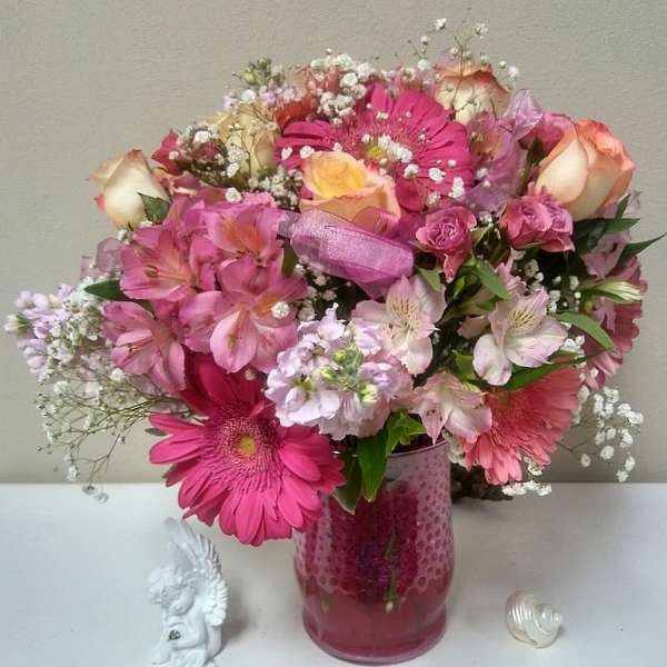 Pink and peach mixed bouquet in a pink glass vase