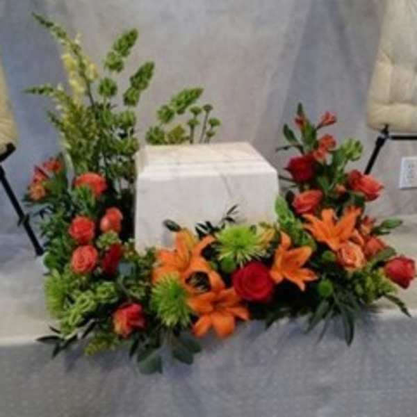 Floral arrangement with orange lilies and red roses around a white box