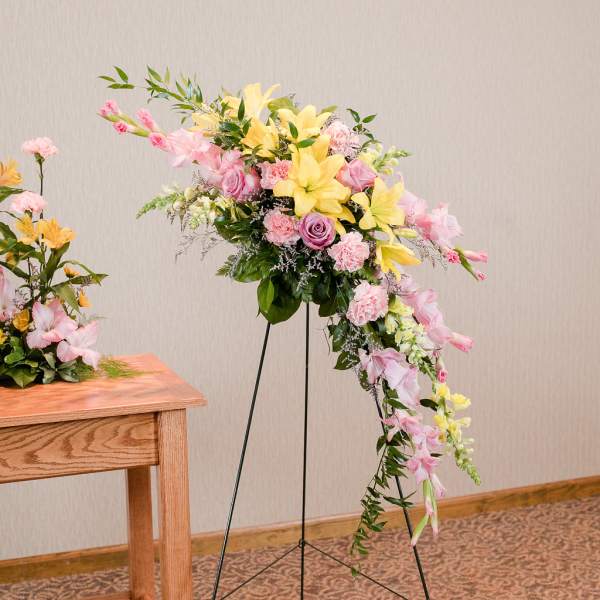 Large pastel floral spray on a stand with pink and yellow flowers
