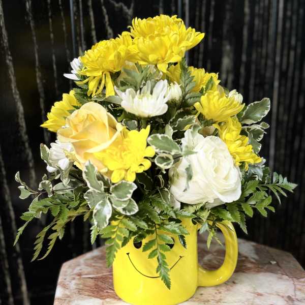 Yellow and white flowers in a smiley-face mug