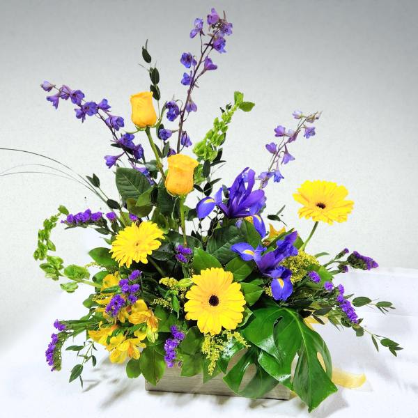 Yellow and purple mixed flower arrangement in a rectangular container