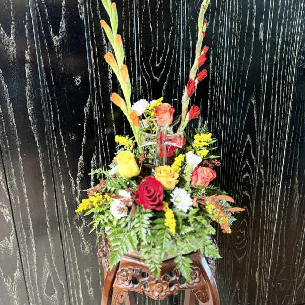 Tall floral arrangement with roses and gladiolus in a clear vase