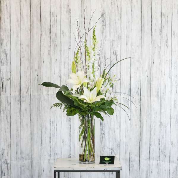 Tall white lily arrangement in a clear glass vase