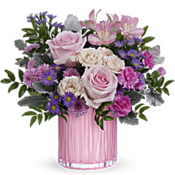 Pink and lavender roses, lilies, carnations, and purple asters in a pink glass cylinder vase