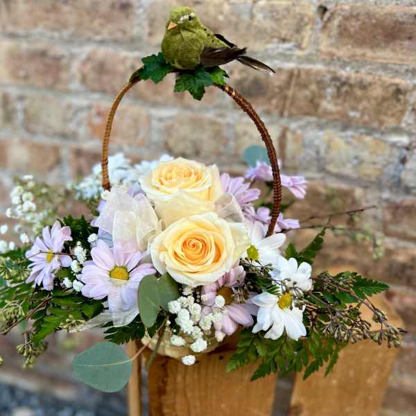 Basket arrangement with pale yellow roses and lavender daisies