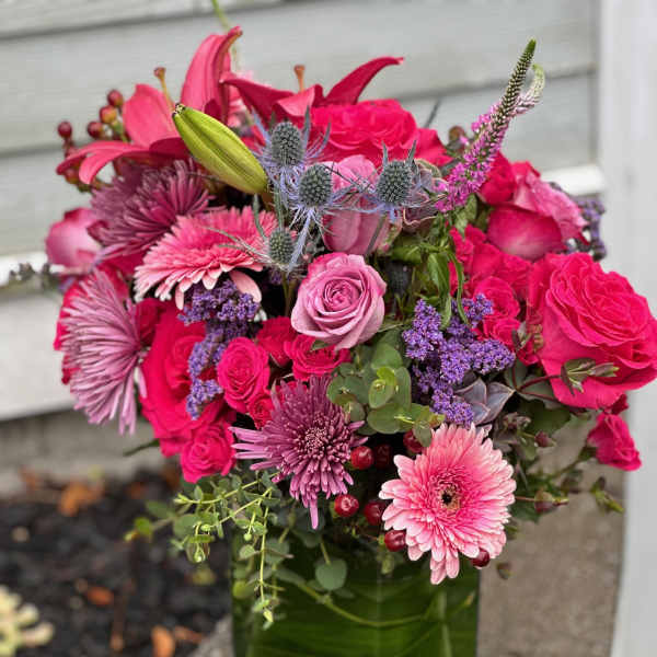 Pink and purple mixed bouquet in a green glass vase