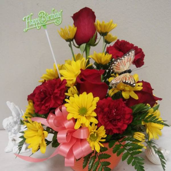 Birthday flower arrangement with red roses and yellow daisies in an orange pot