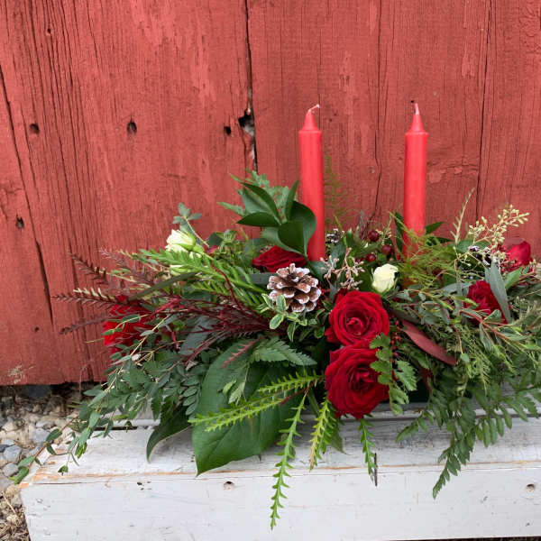 Red roses and greenery arranged with two red candles
