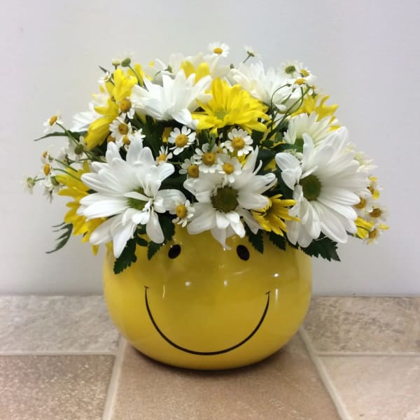Yellow smiley-face container filled with white and yellow daisies