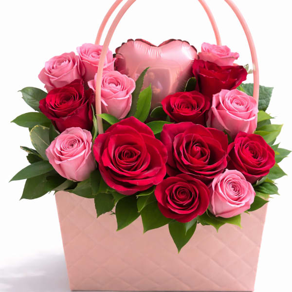 Pink and red roses arranged in a pink gift basket with a heart balloon
