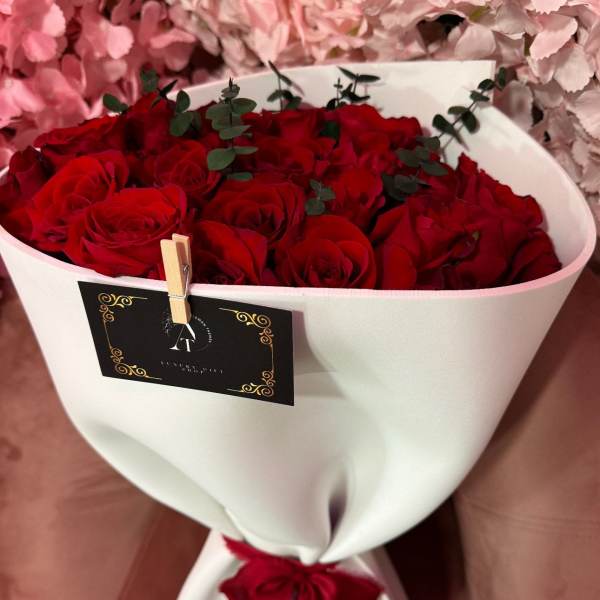 Bouquet of red roses wrapped in white paper with a red ribbon