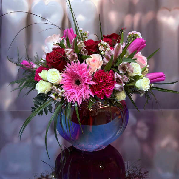 Mixed pink and red bouquet in a round glass vase
