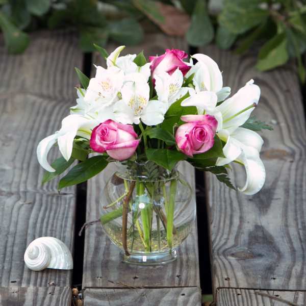 Pink roses and white lilies arranged in a clear glass vase