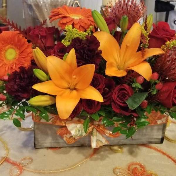 Orange and red mixed flower arrangement in a rectangular box