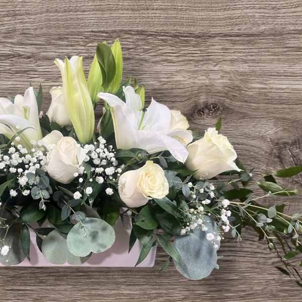 White roses and lilies in a low rectangular vase arrangement