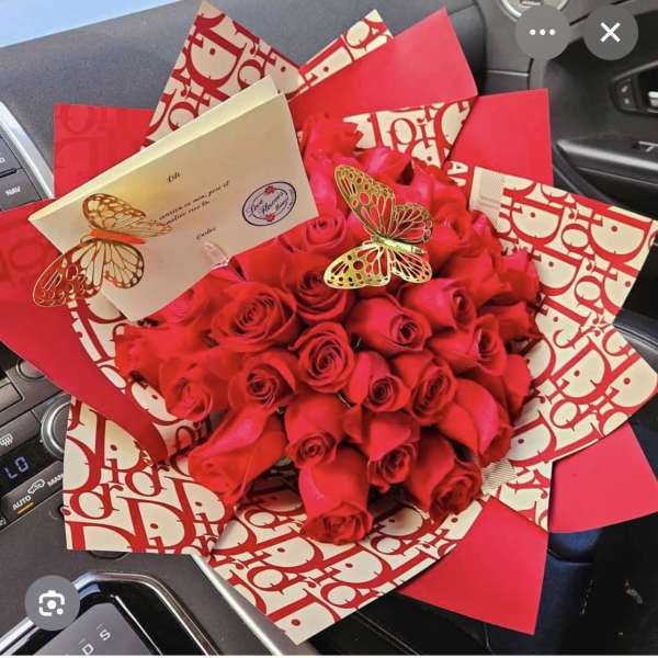 Bouquet of red roses wrapped in red and cream paper with butterfly accents