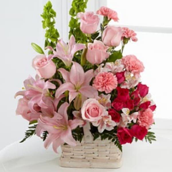 Pink lilies, roses, and carnations in a white basket