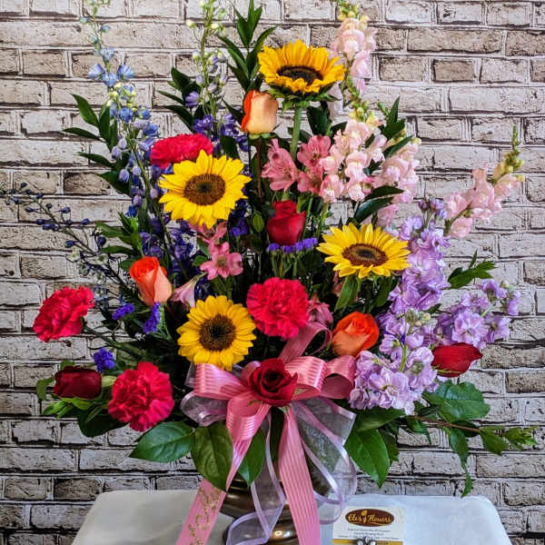 Colorful mixed flower arrangement in a vase with a pink ribbon