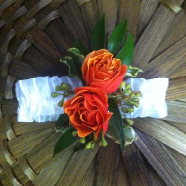 Two orange roses with greenery on a woven basket background