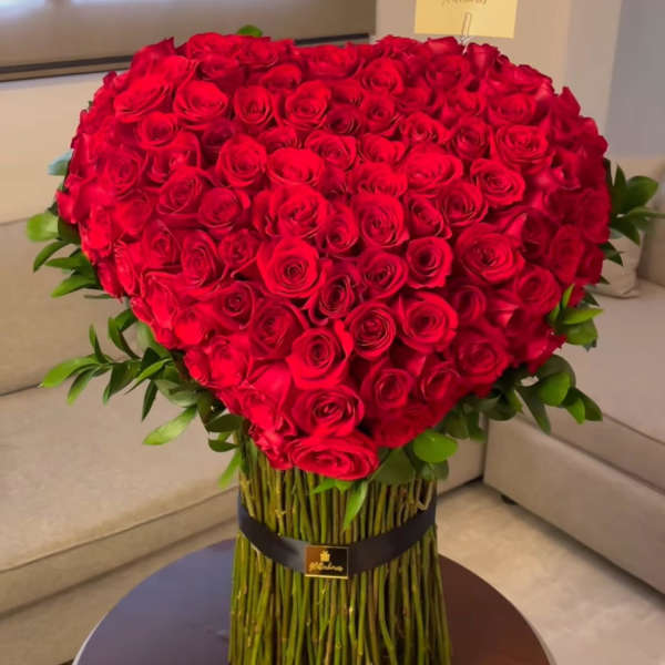 Large heart-shaped bouquet of red roses with green foliage
