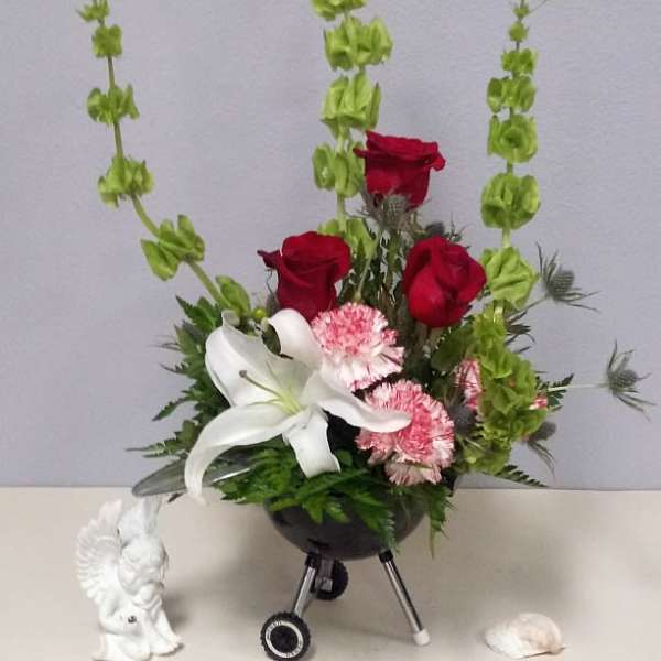 Arrangement of red roses, white lily, and pink flowers in a black vase