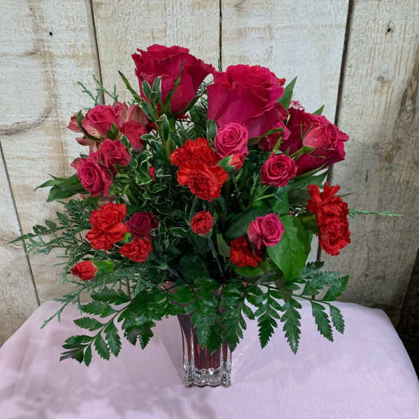 Red roses and carnations arranged in a clear glass vase
