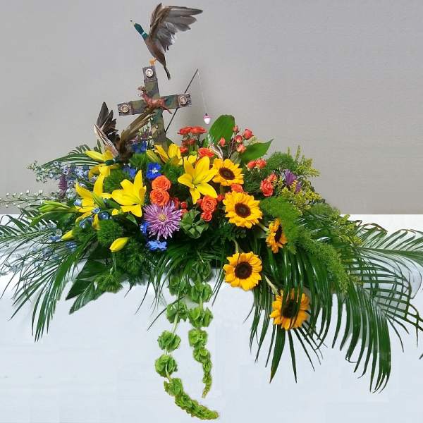 Floral arrangement with sunflowers, lilies, and a cross topper