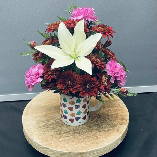 Bouquet of red and pink flowers in a heart-pattern mug