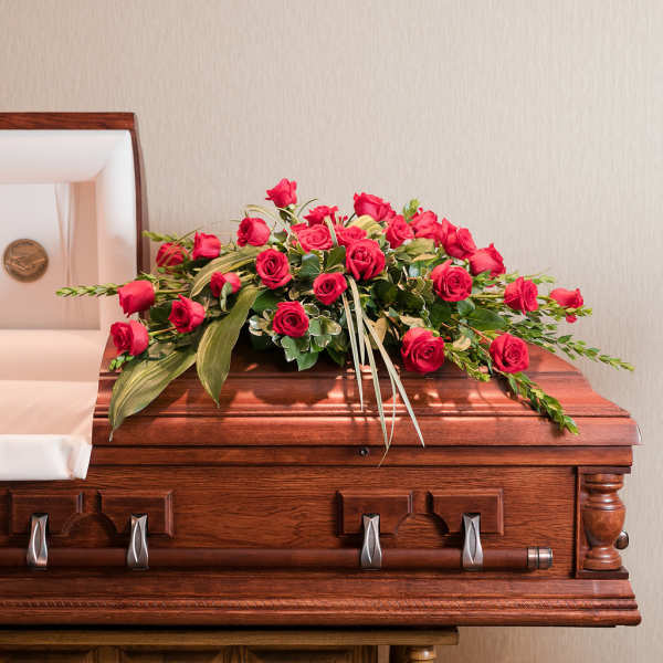 Red rose spray arranged on a wooden casket