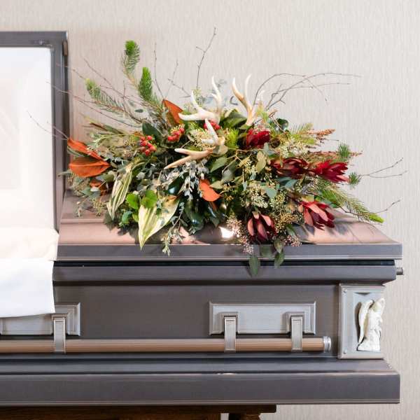 Floral spray on top of a casket with red and green accents