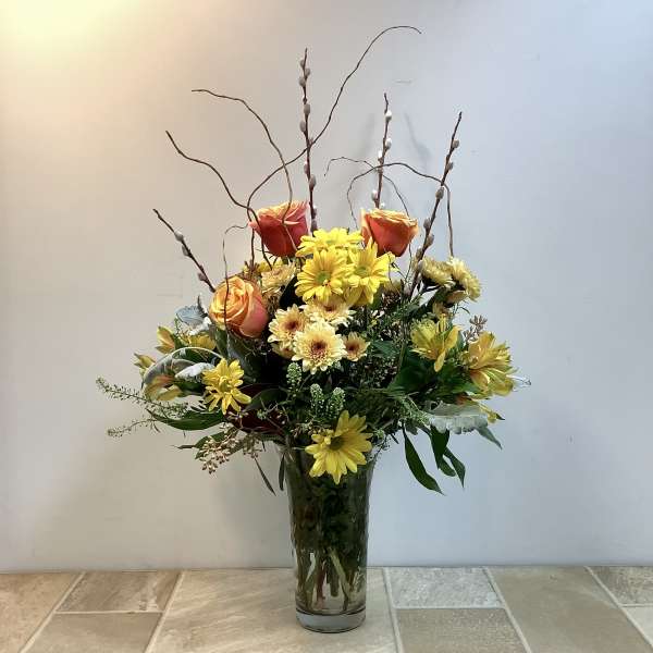 Mixed bouquet of yellow and orange flowers in a clear glass vase