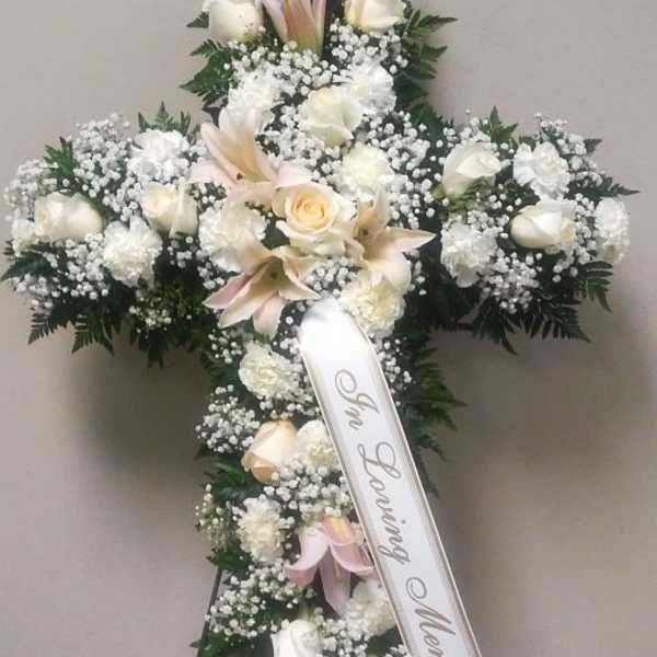 White floral funeral cross with a memorial ribbon